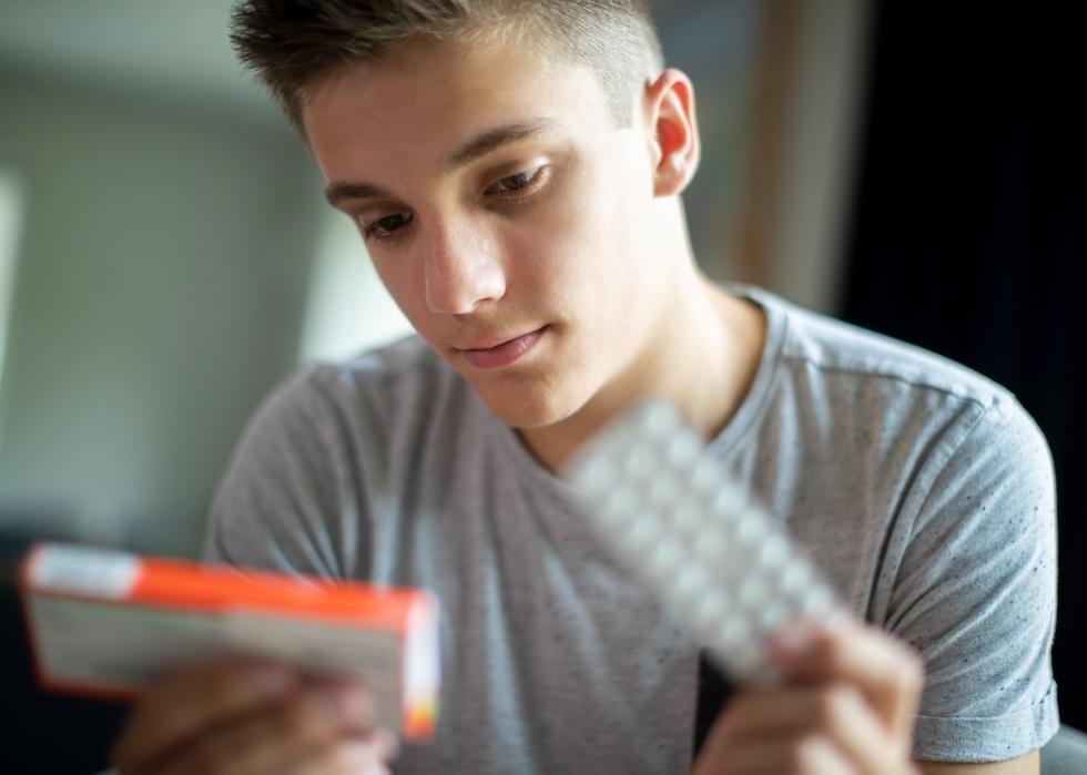 Teenage boy looking at prescription medication box