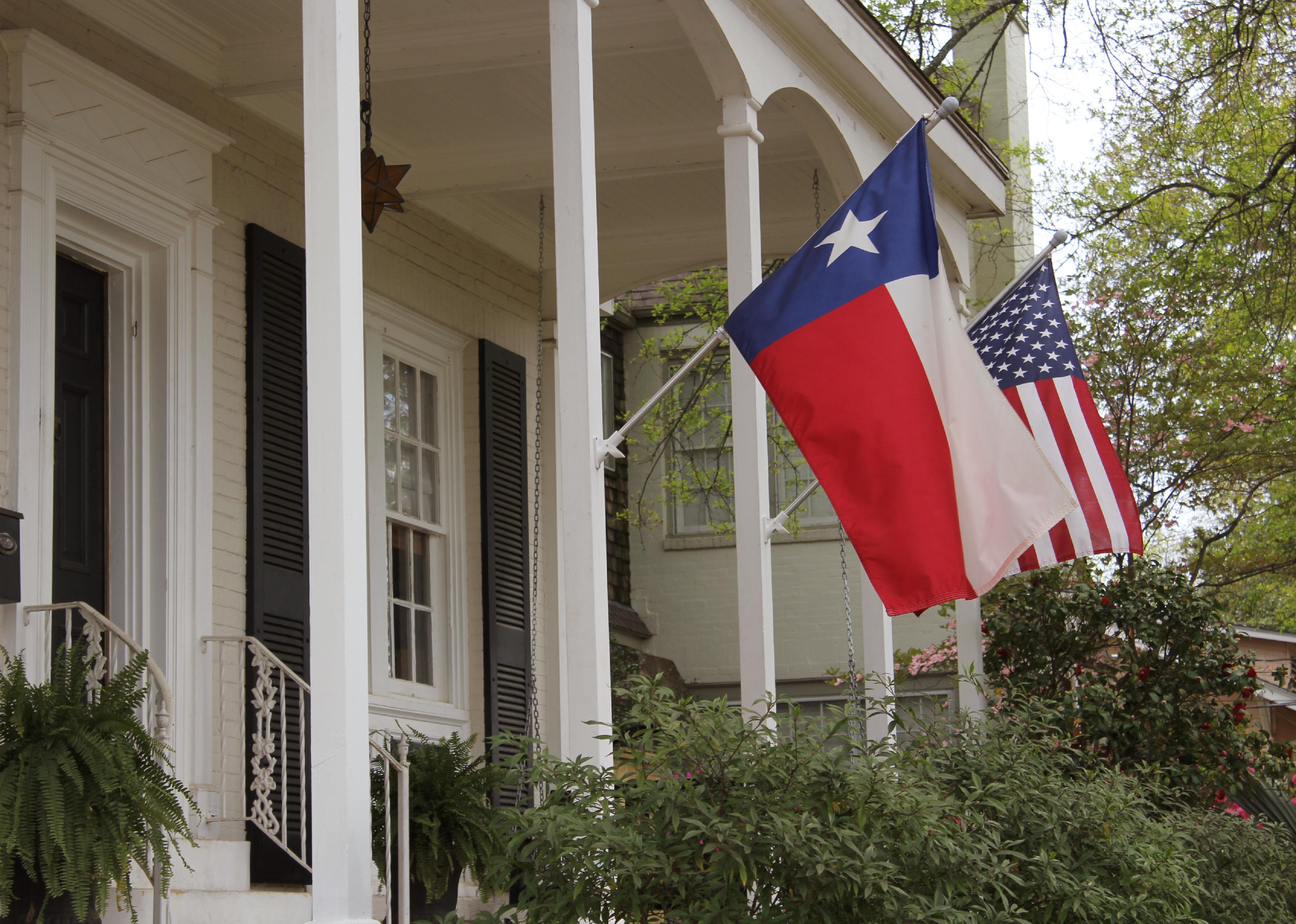 Historic home with Texas and American flags.