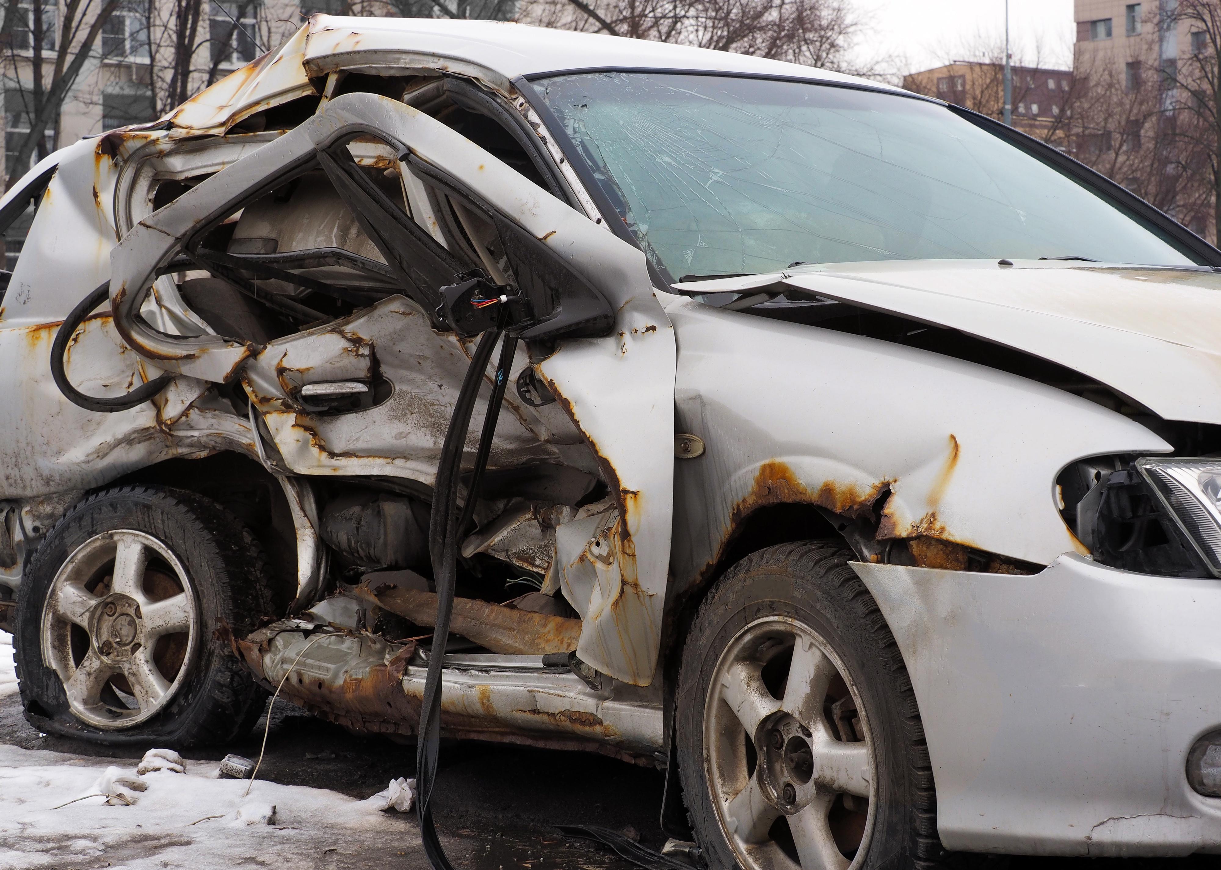 Warped, flattened white car after a car accident.