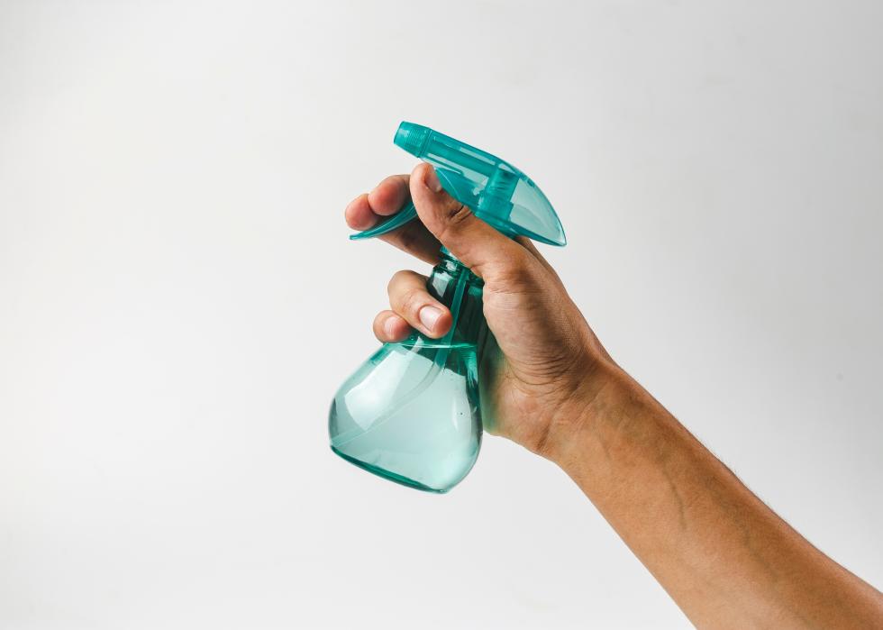 Hand holding plastic spray bottle.