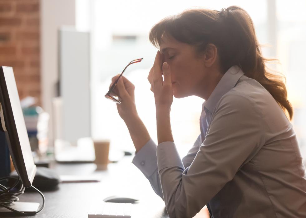 Exhausted woman worker sitting at her office desk.