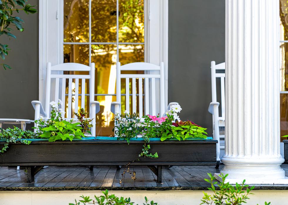 Detailed view of flower boxes and rocking chairs on porch.