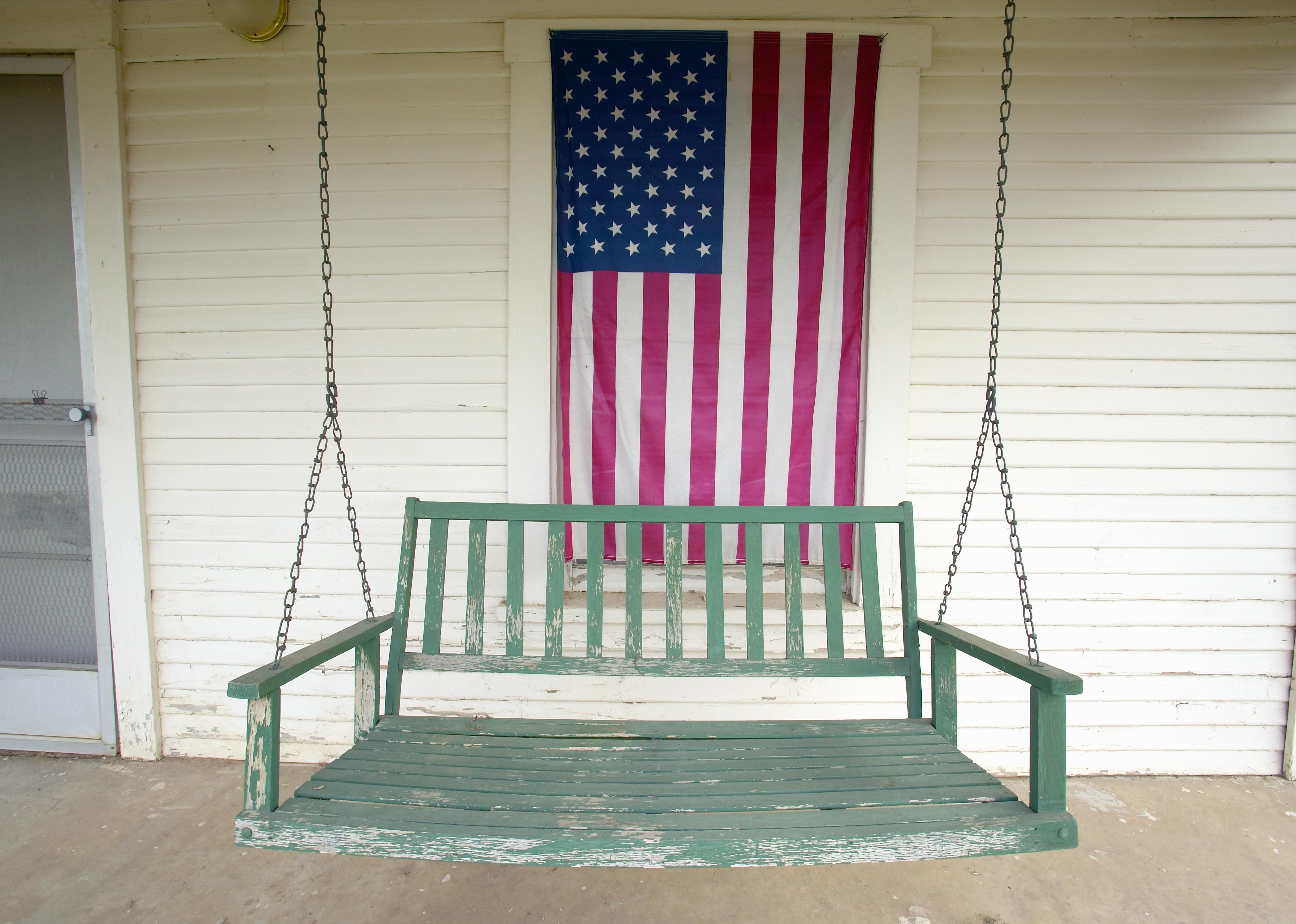  Old swing on porch displaying an American flag