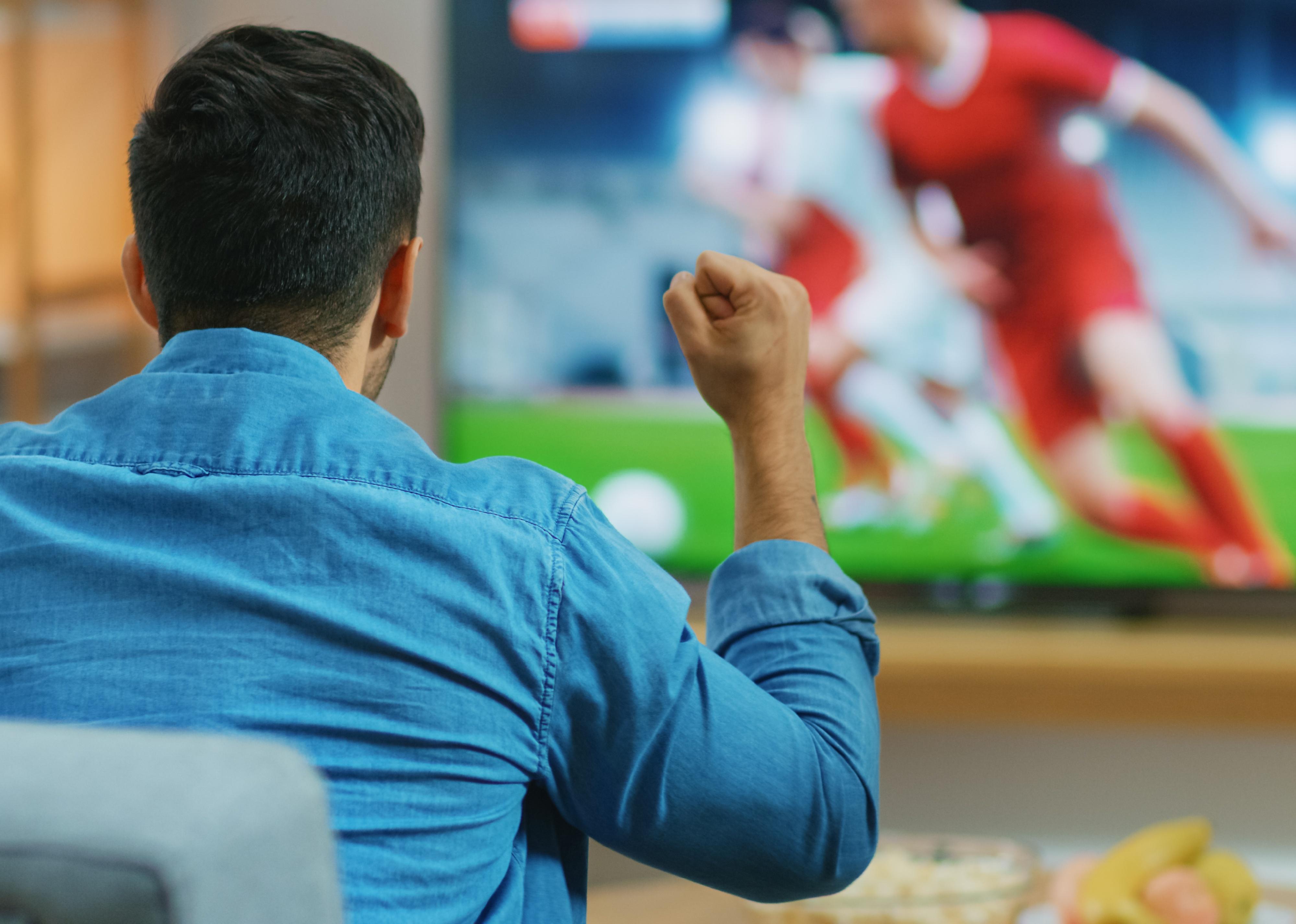 Man watches soccer match on TV.
