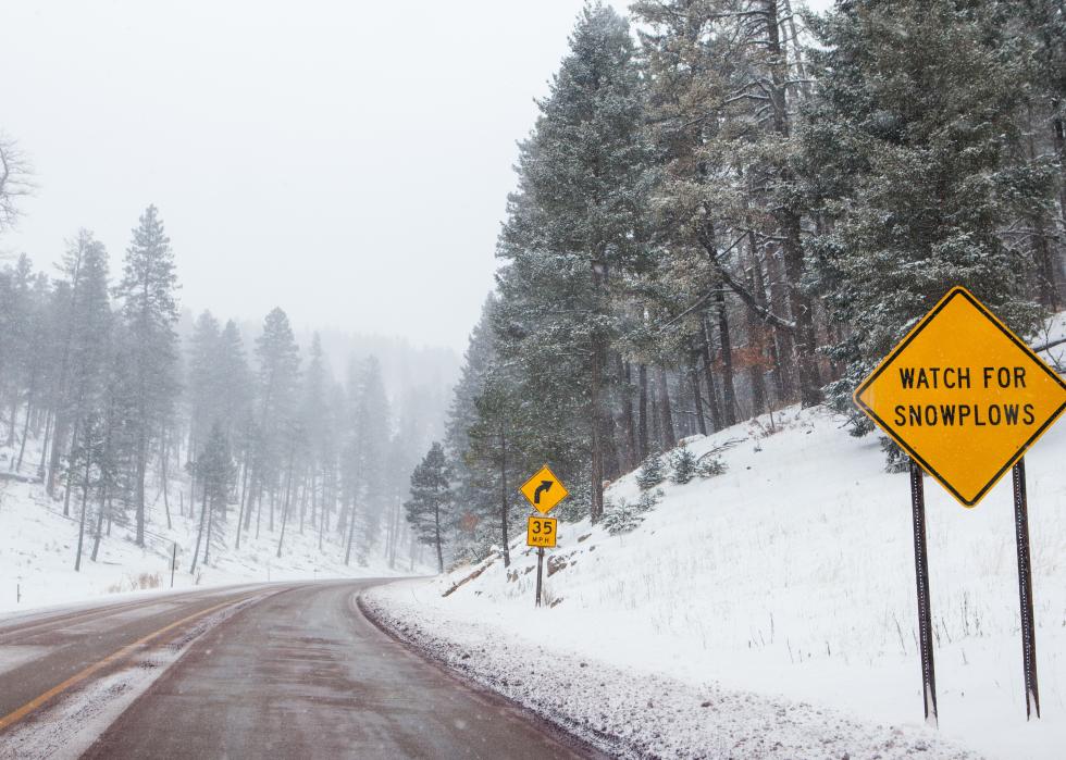 A snowy mountain road with warning signs in New Mexico.