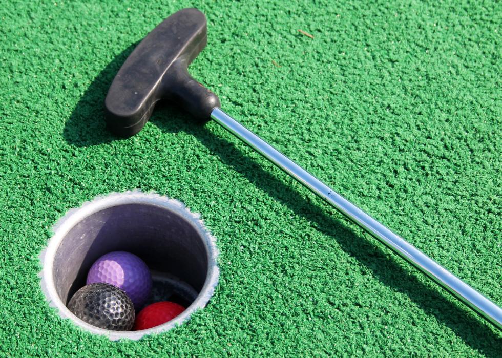 Mini golf balls in a hole with a putt nearby