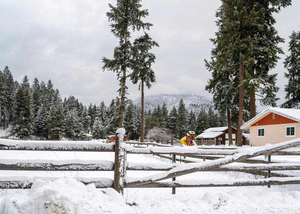 A winter scene of a country ranch home and barn covered in snow in the mountains of North Idaho.