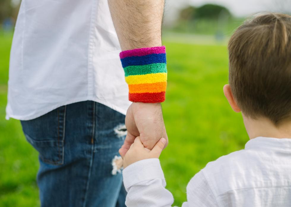Close up of man wearing rainbow-colored wrist sweatband holding little boy's hand