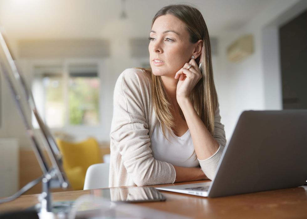 Woman at home looking away from her laptop