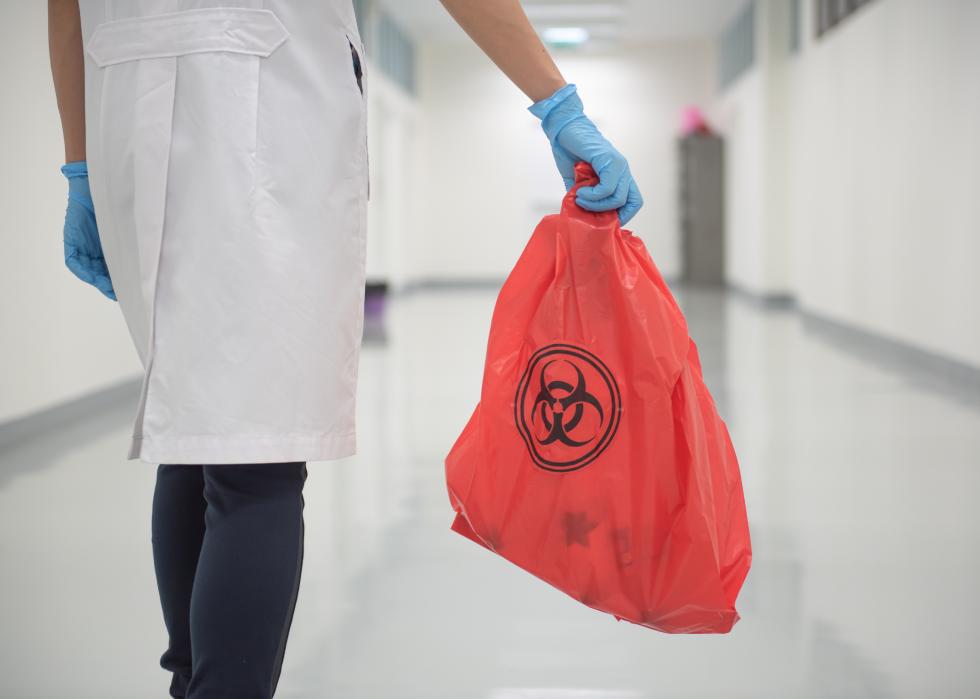 A woman holding a red bag with biohazard sign in the hospital.