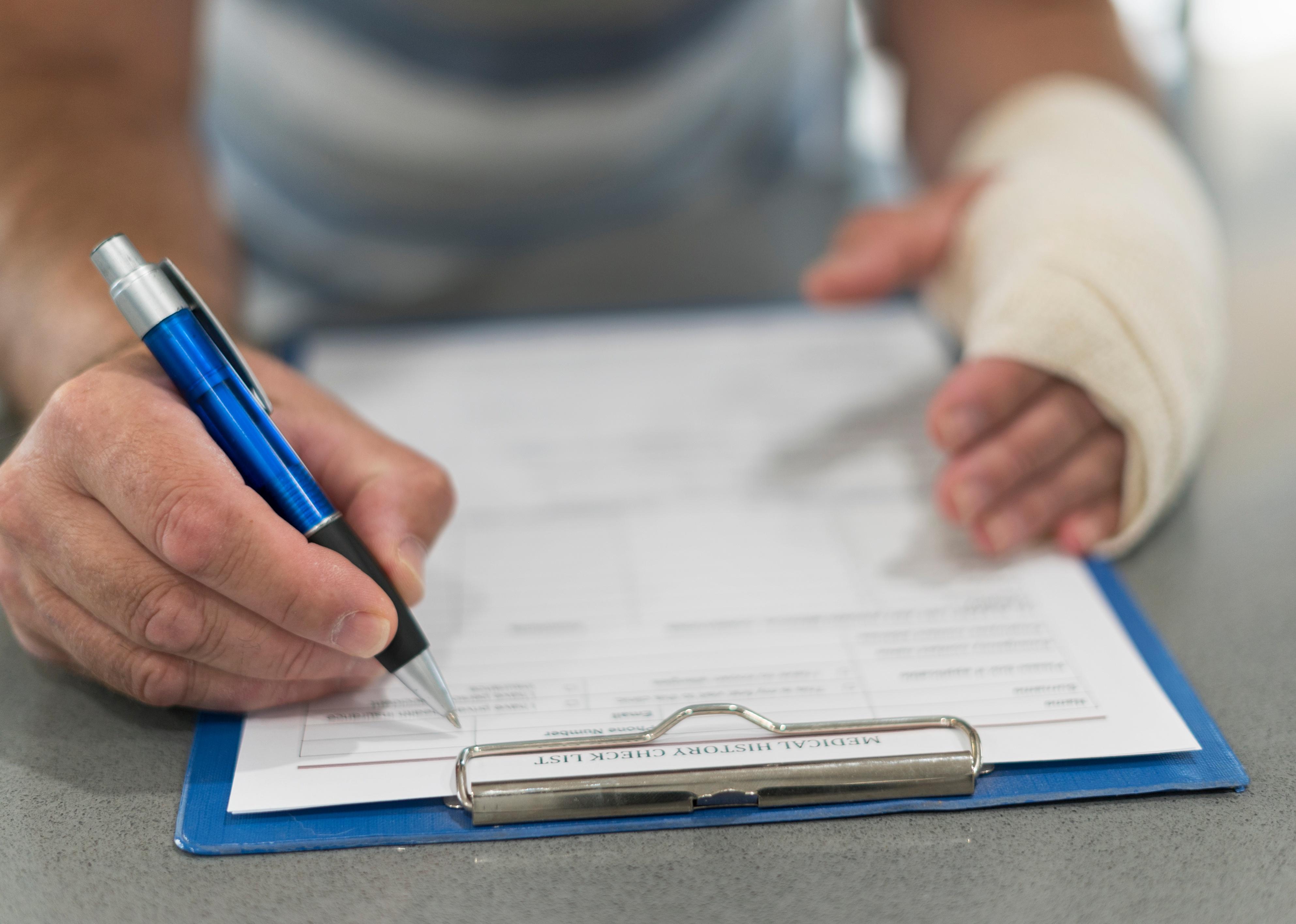 A person filling in medical forms after an injury.