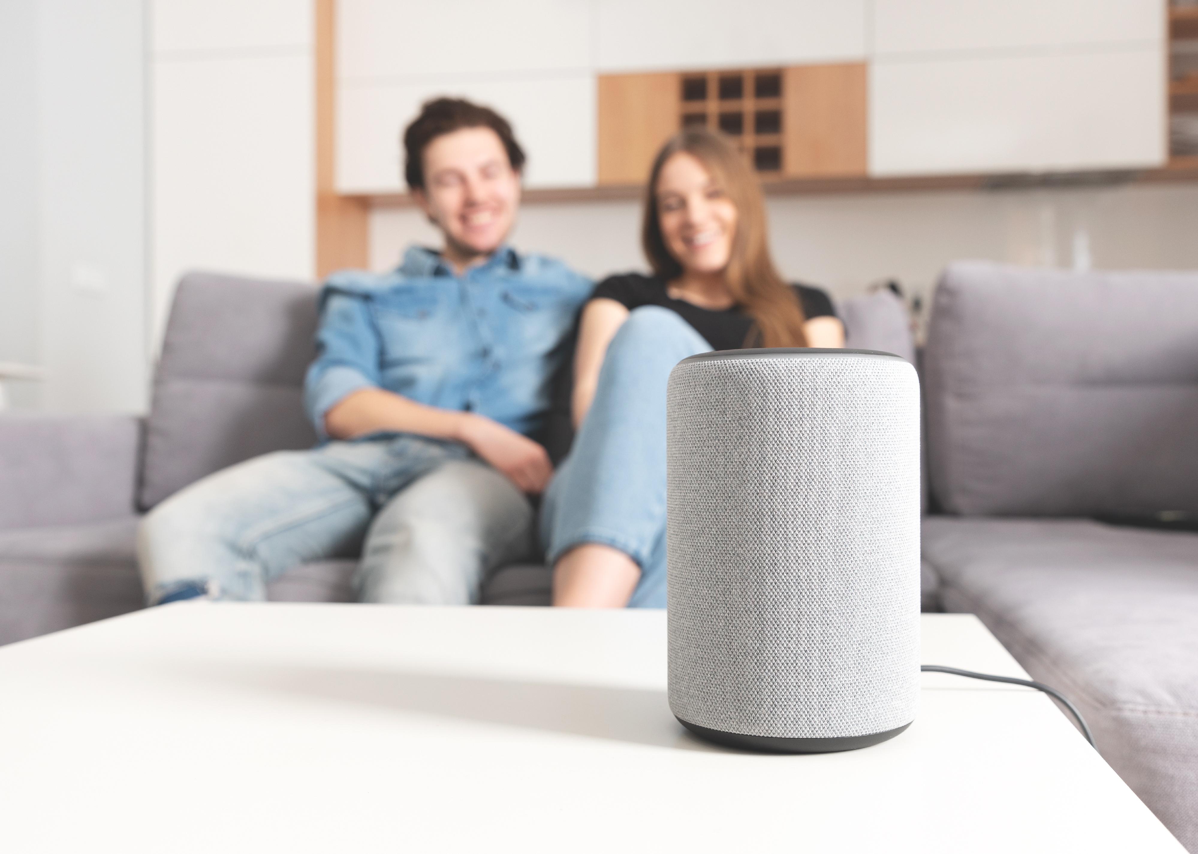 Couple talking command to smart speaker.