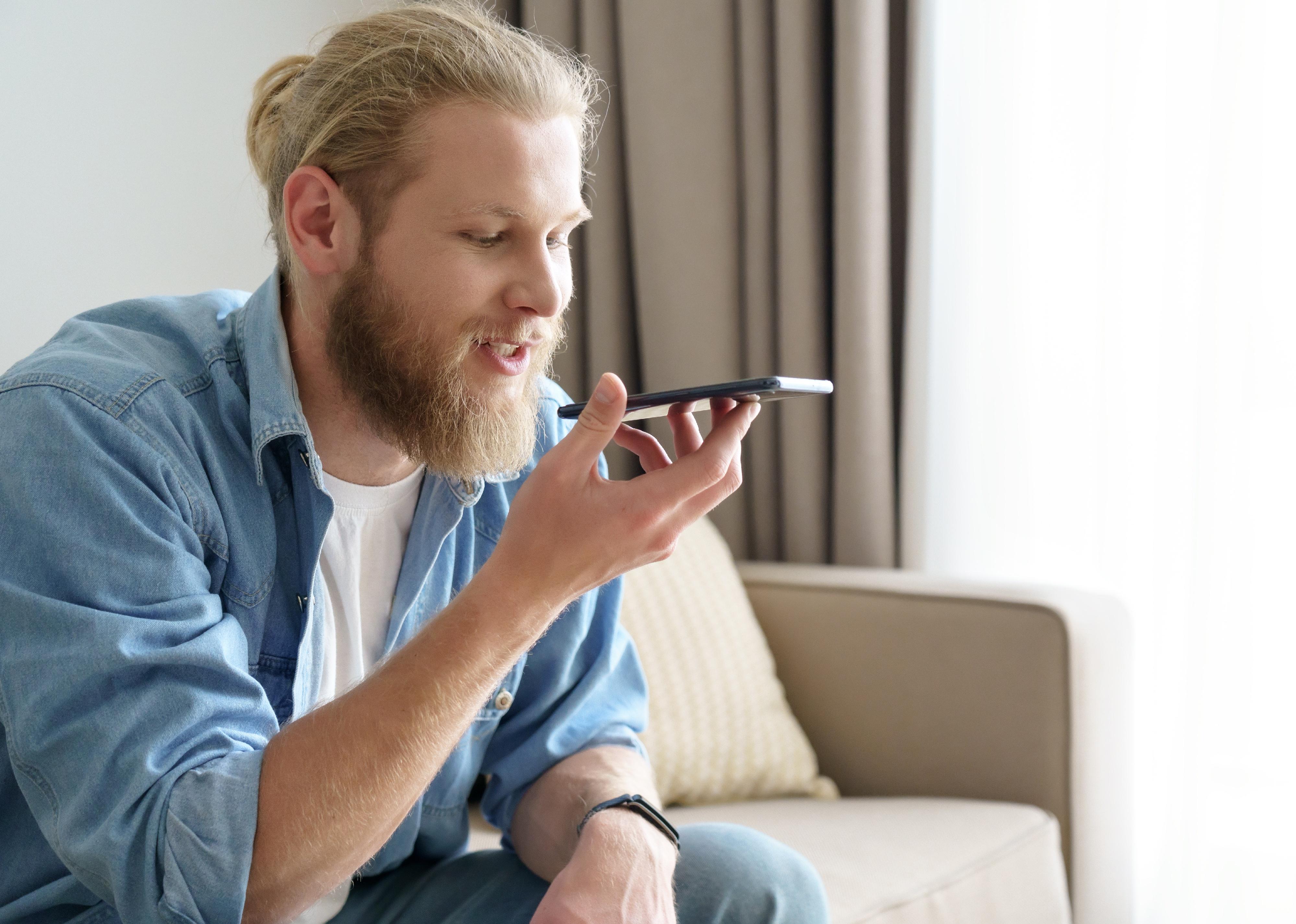 Young man holding smart phone speak on speakerphone.