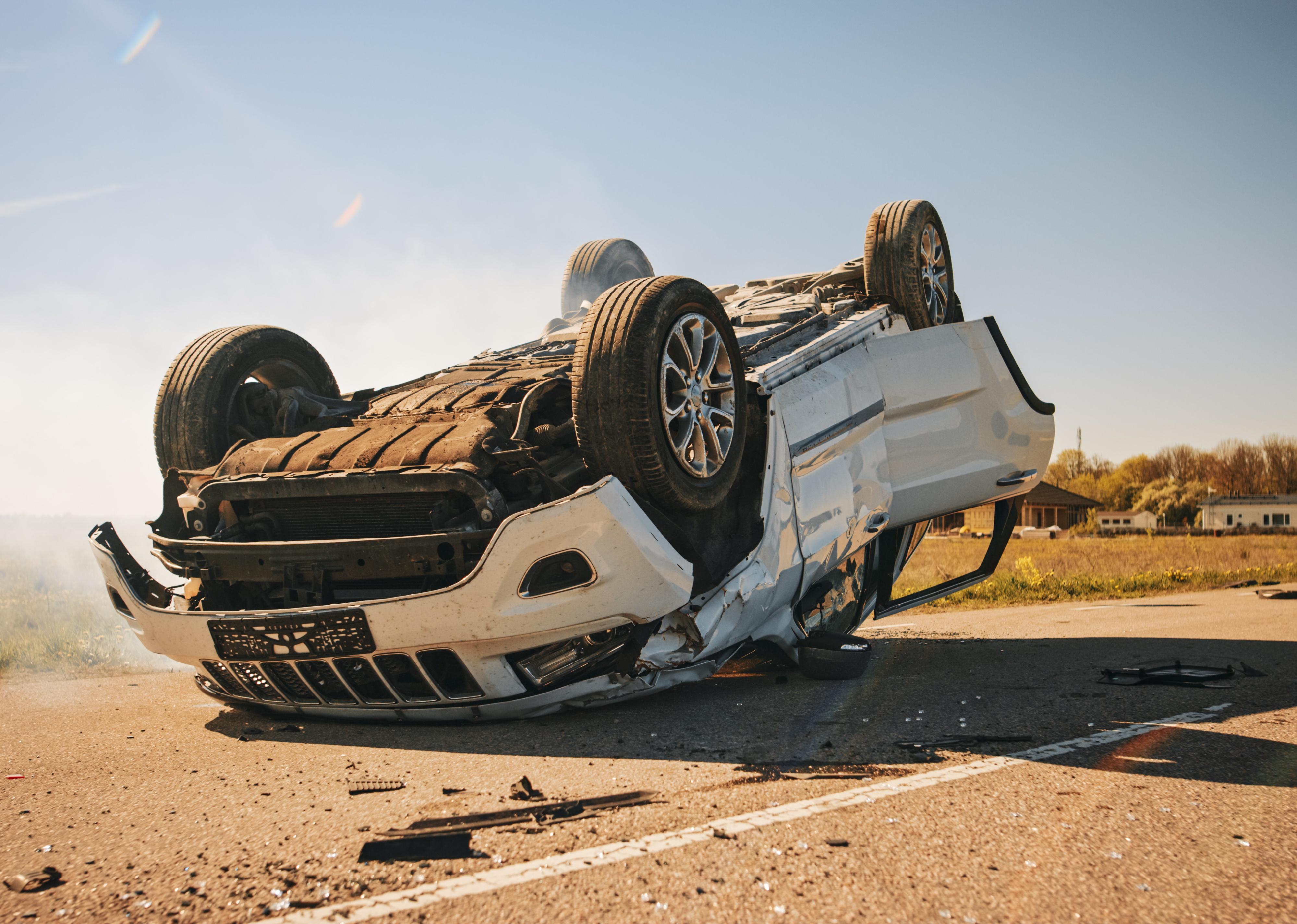 Vehicle lying on its roof in the middle of the road.