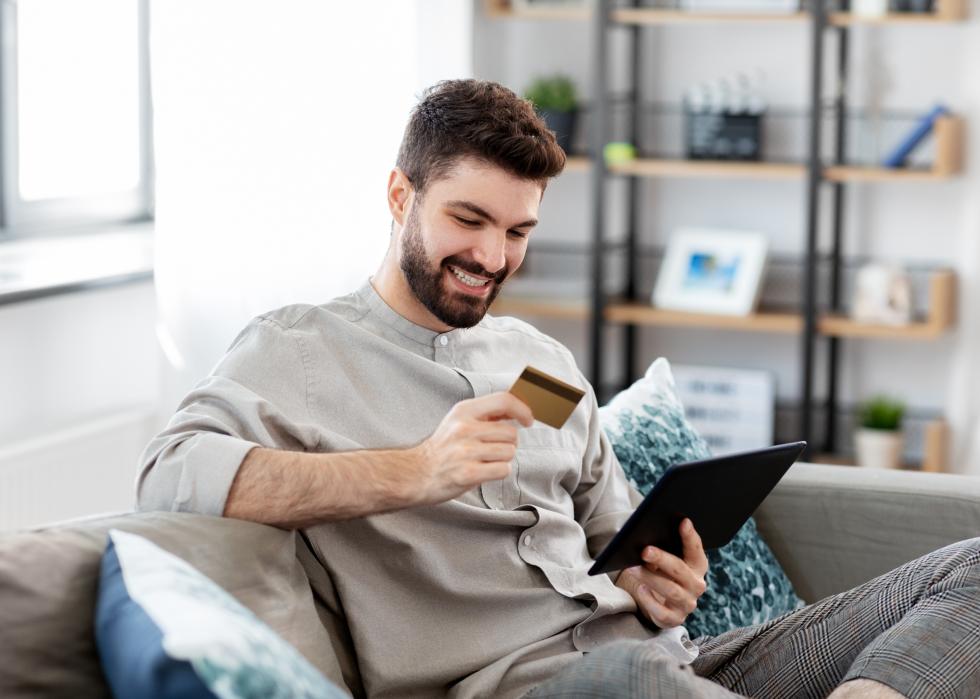 Smiling man with tablet and credit card at home