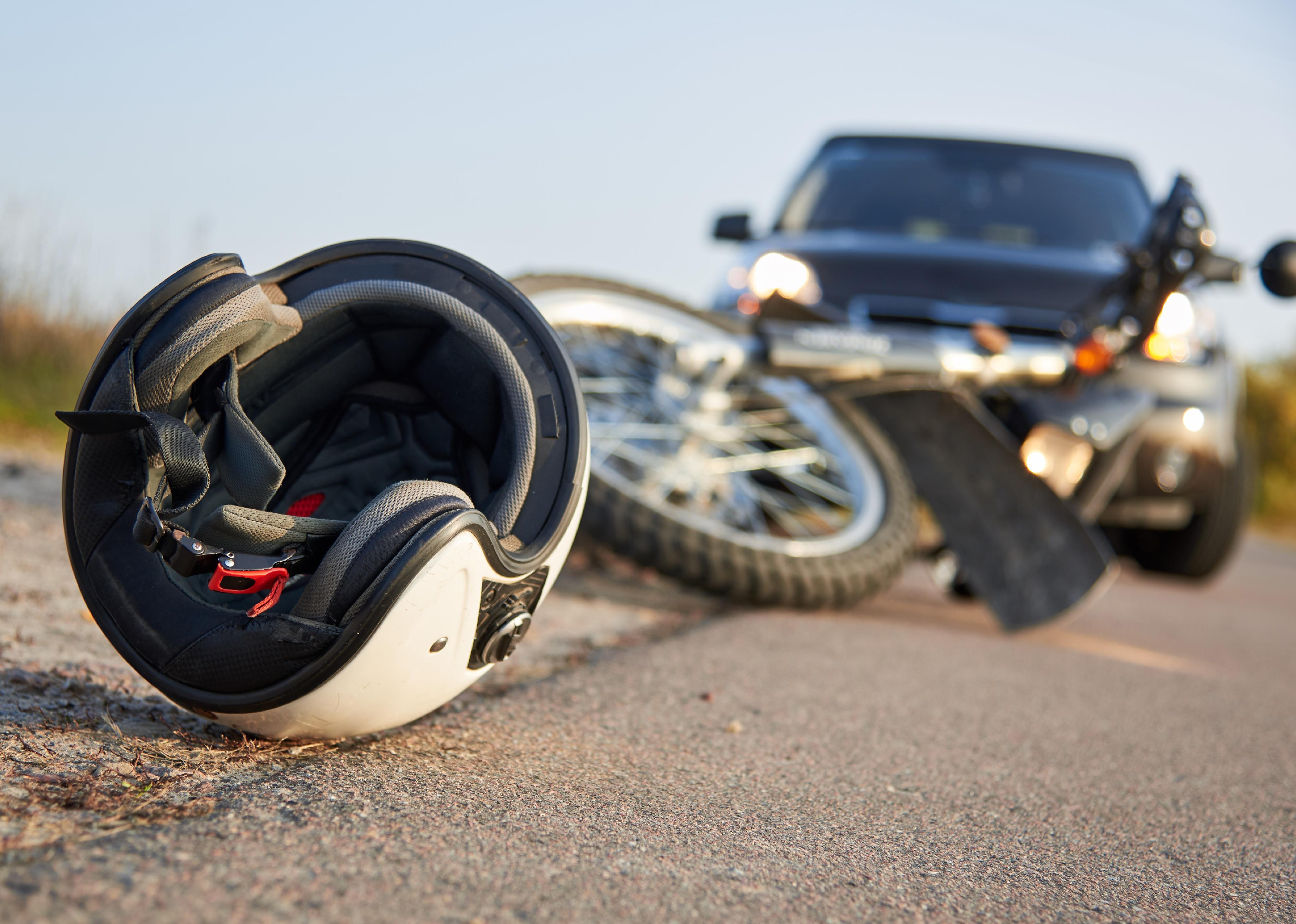 Photo of a car, helmet and motorcycle on road.