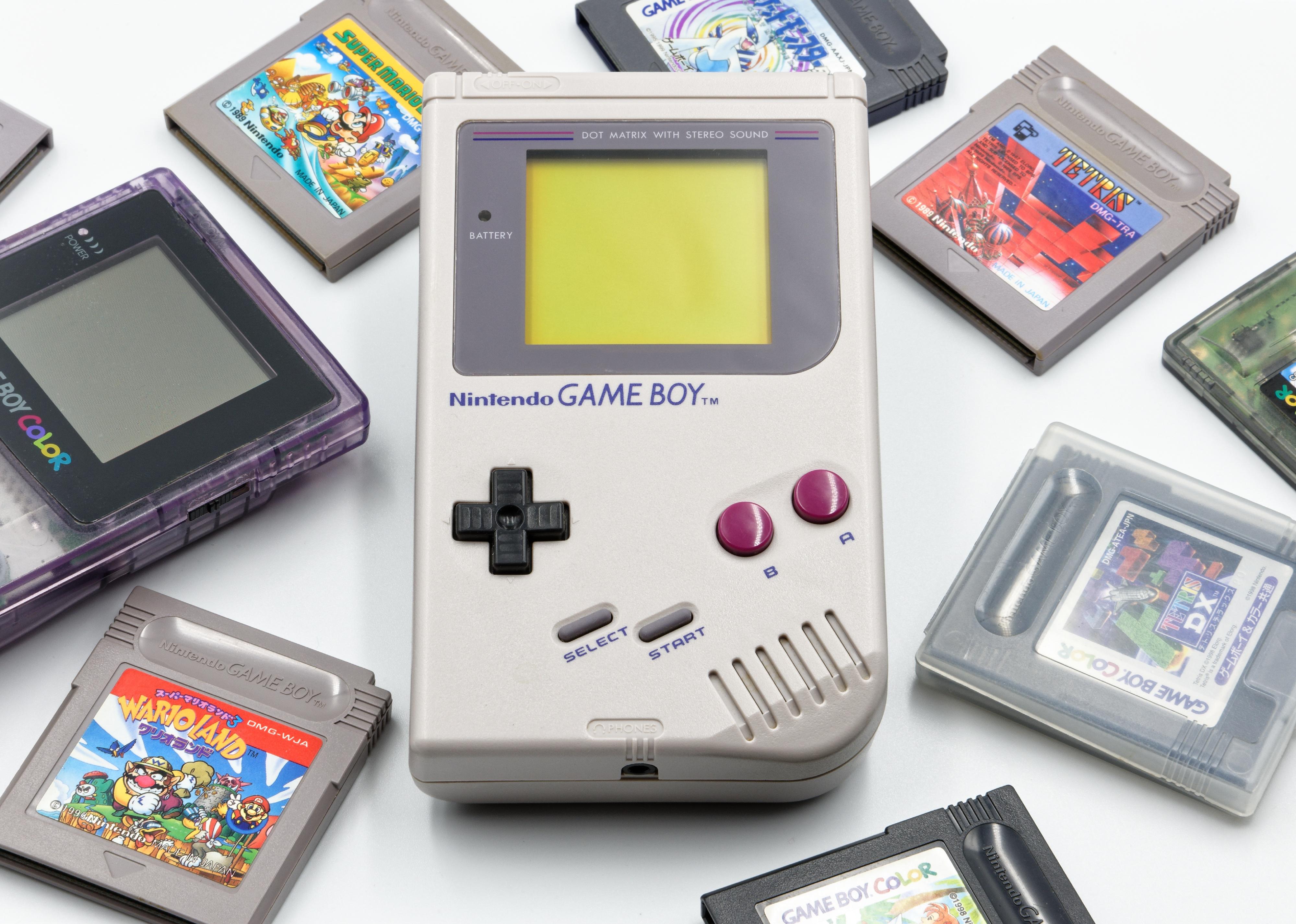 Nintendo Game Boy and several game cartridges on white background.