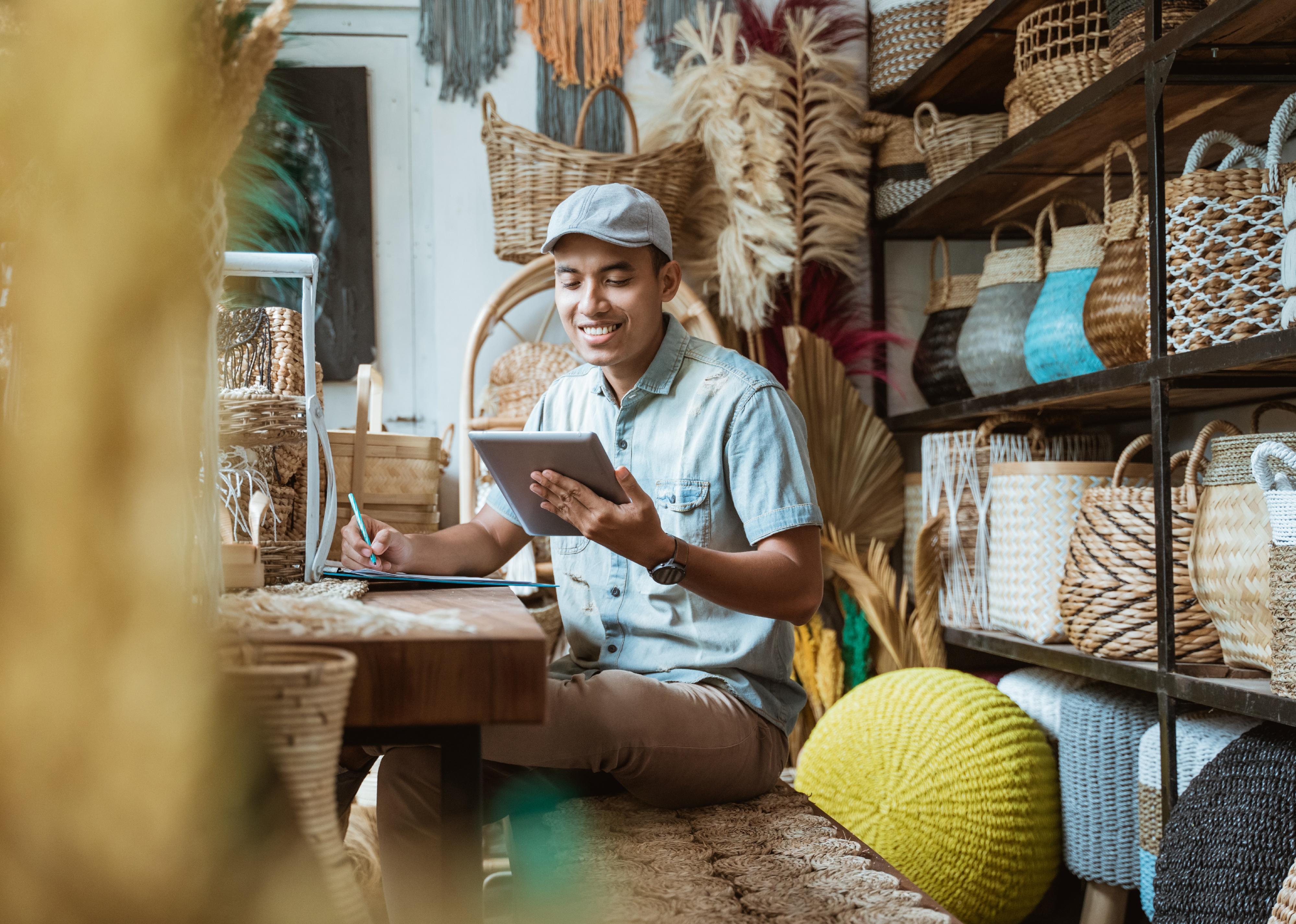 Shop owner takes notes with a pen while using a digital tablet. 