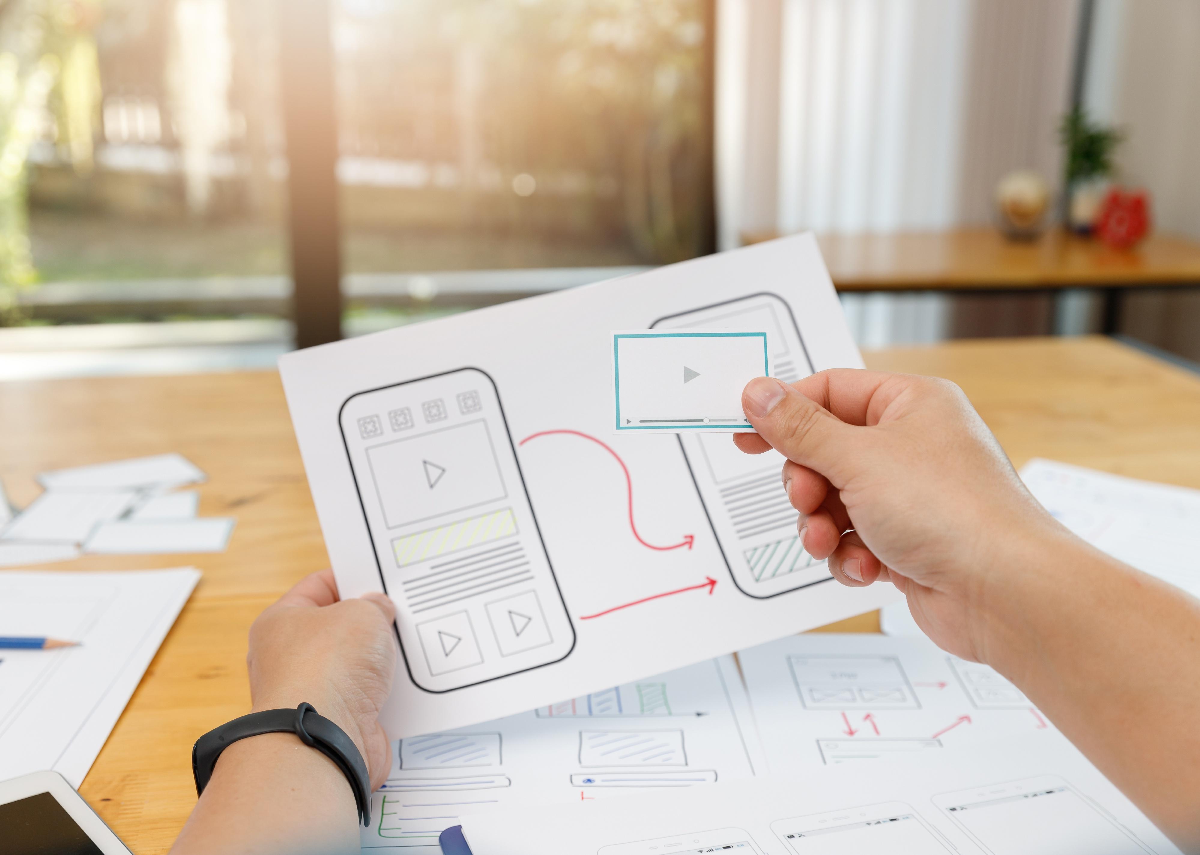 Hands holding plans for app layout.