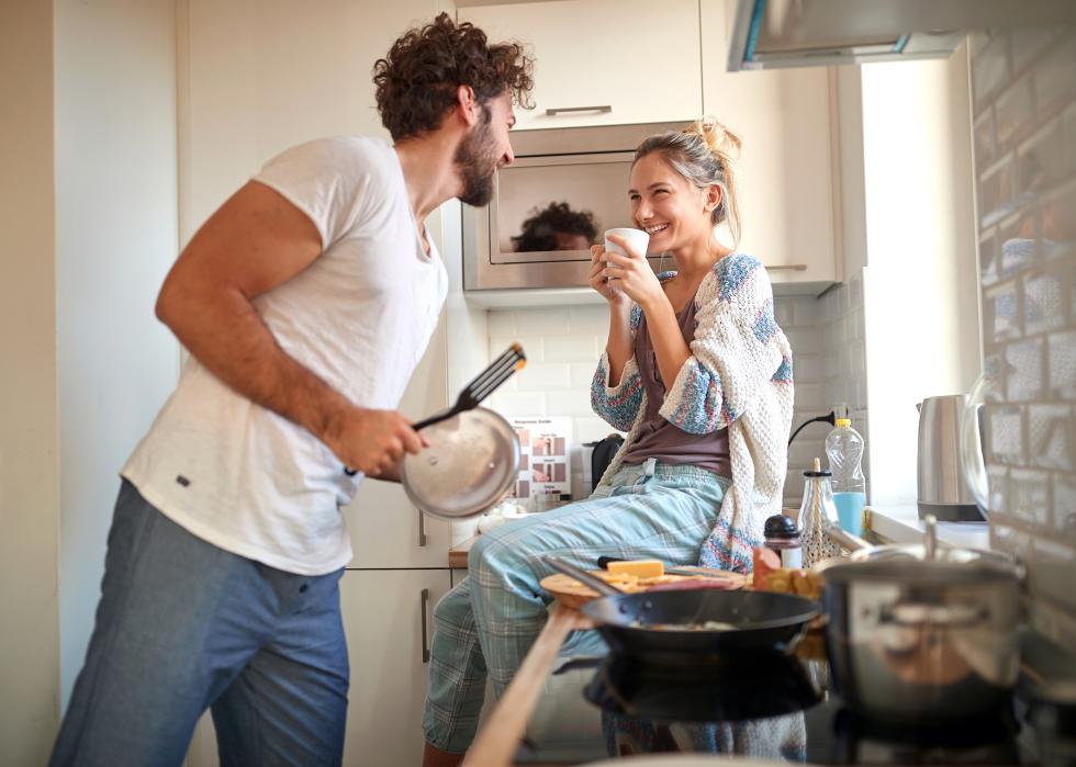 A young couple having fun while making breakfast.