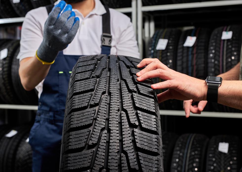 Close up of hands on tires in shop.