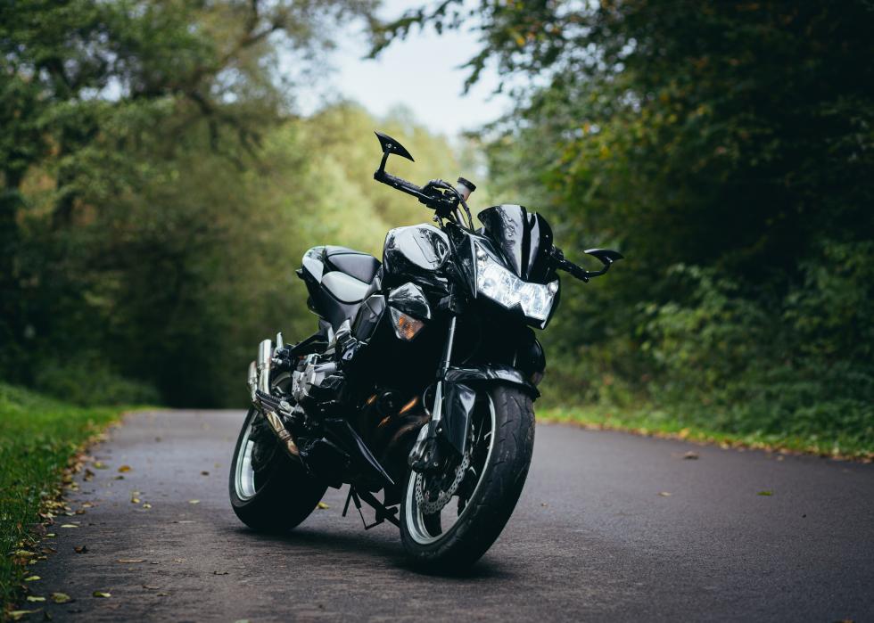 Black sports motorcycle standing on a forest road.