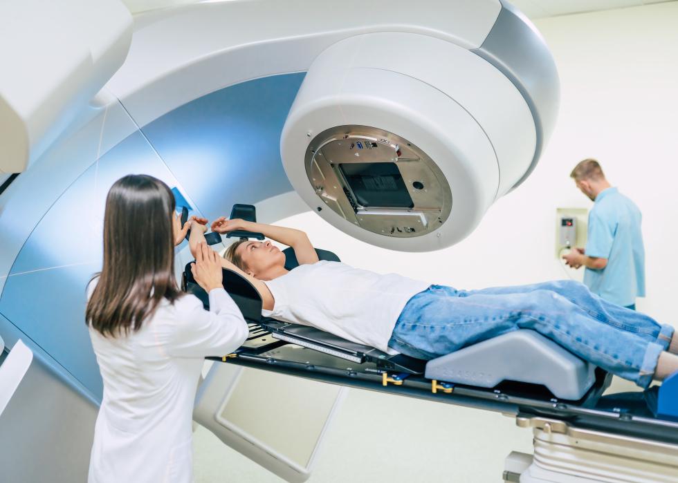 Two people helping a woman undergo radiation therapy.