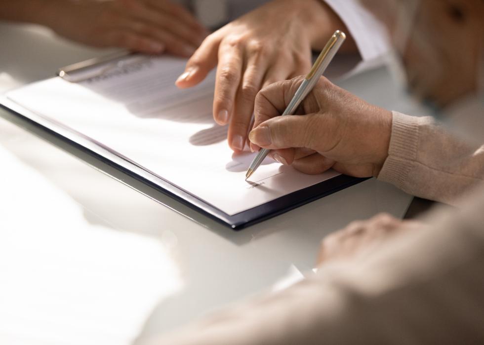 Close up of a patient's hand signing medical insurance contract.