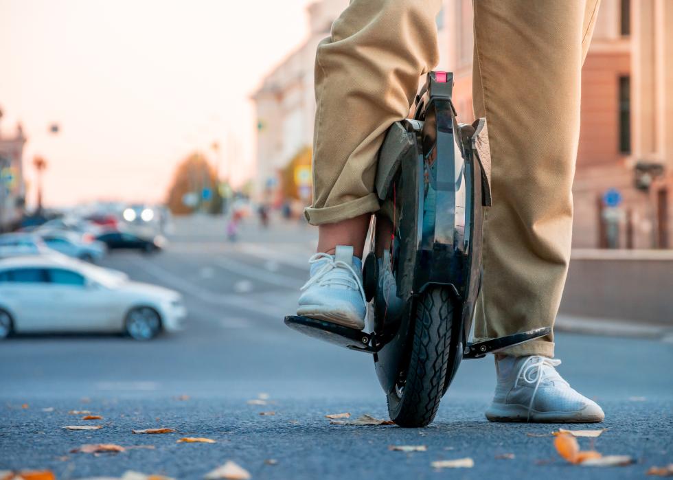 The legs of a young woman on an electric unicycle.