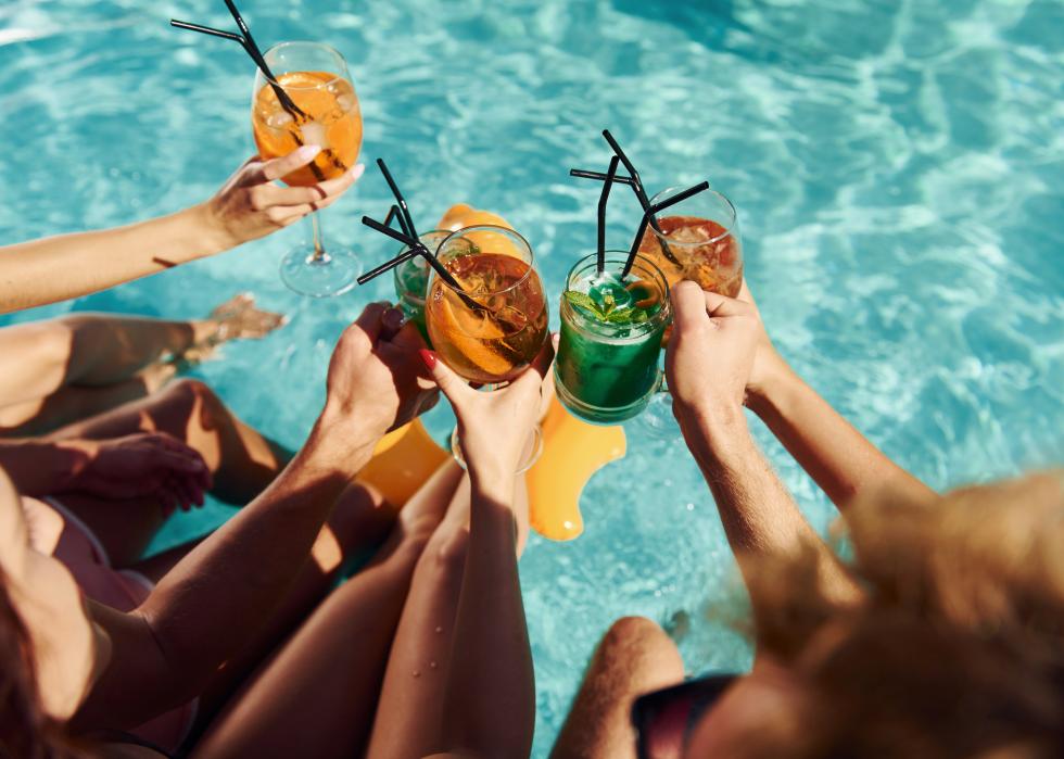 Top view of group of people with drinks by a pool.