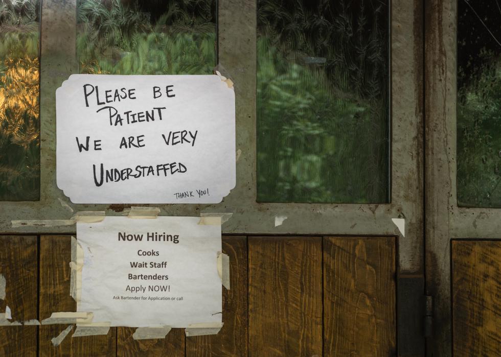 Rustic sign in restaurant stating restaurant is understaffed and hiring.