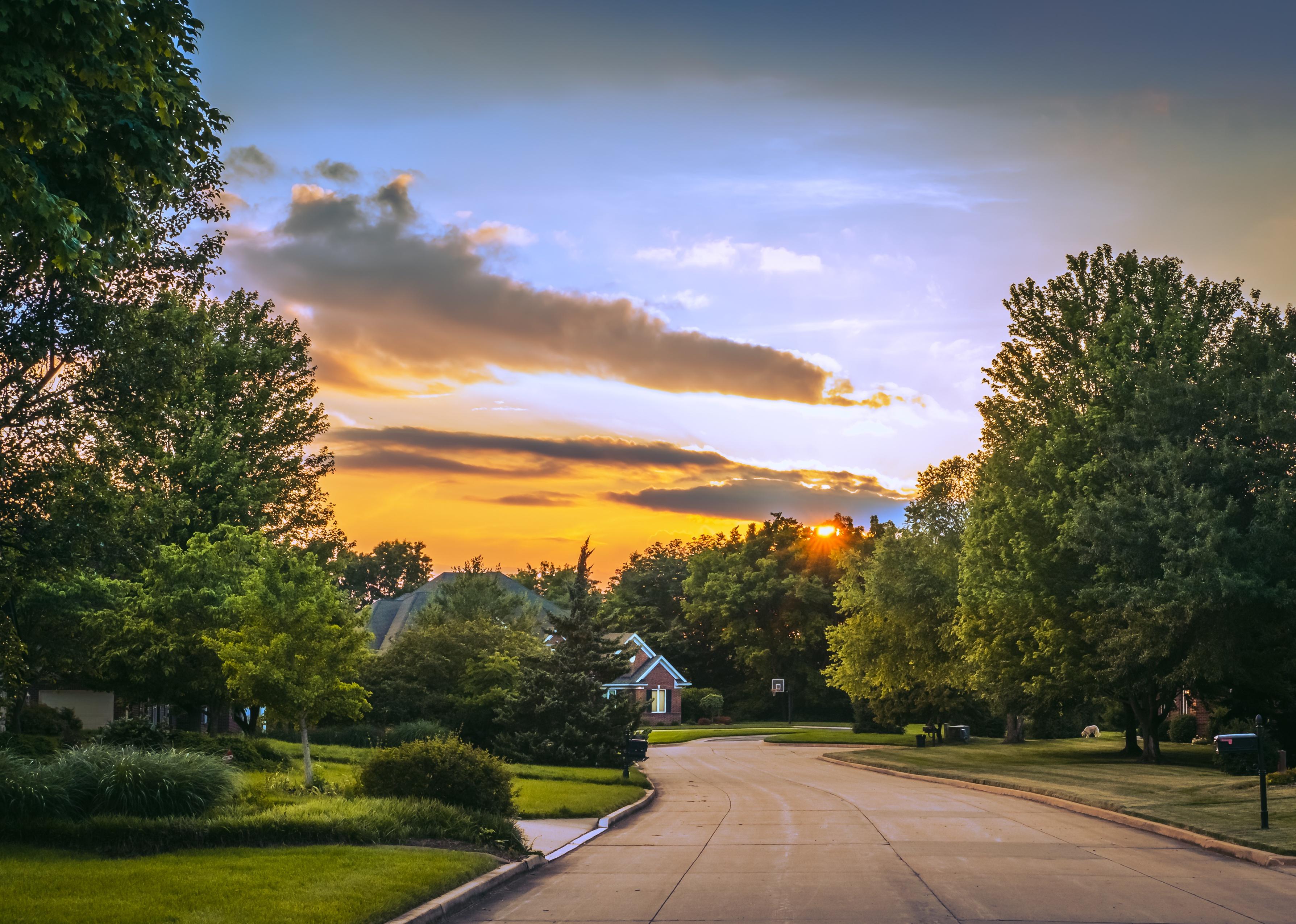 View of street in suburban neighborhood during sunset.