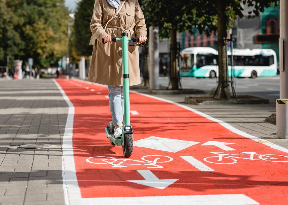 Woman riding electric scooter along red bike lane.