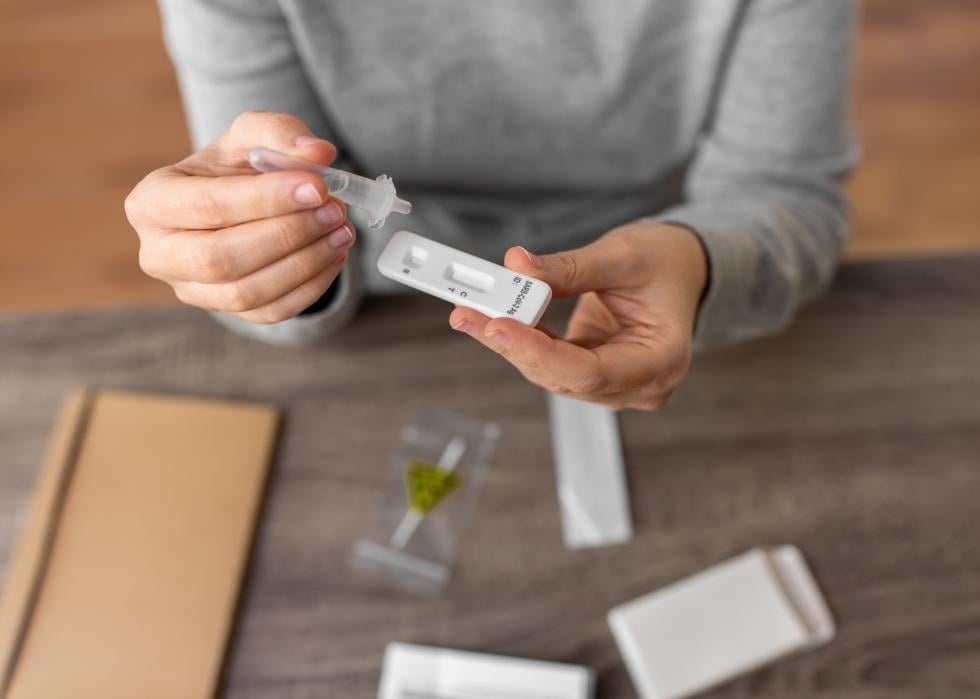 Close up of a person using a coronavirus test, dropping liquid onto the cassette.