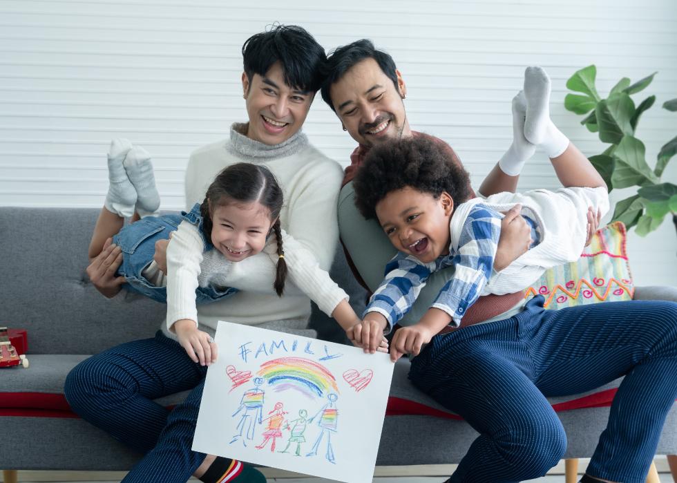 Happy young gay couple playing with kids