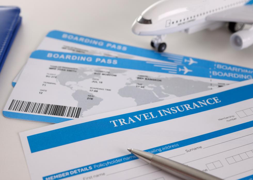 Closeup of airplane tickets and empty travel insurance form with pen.