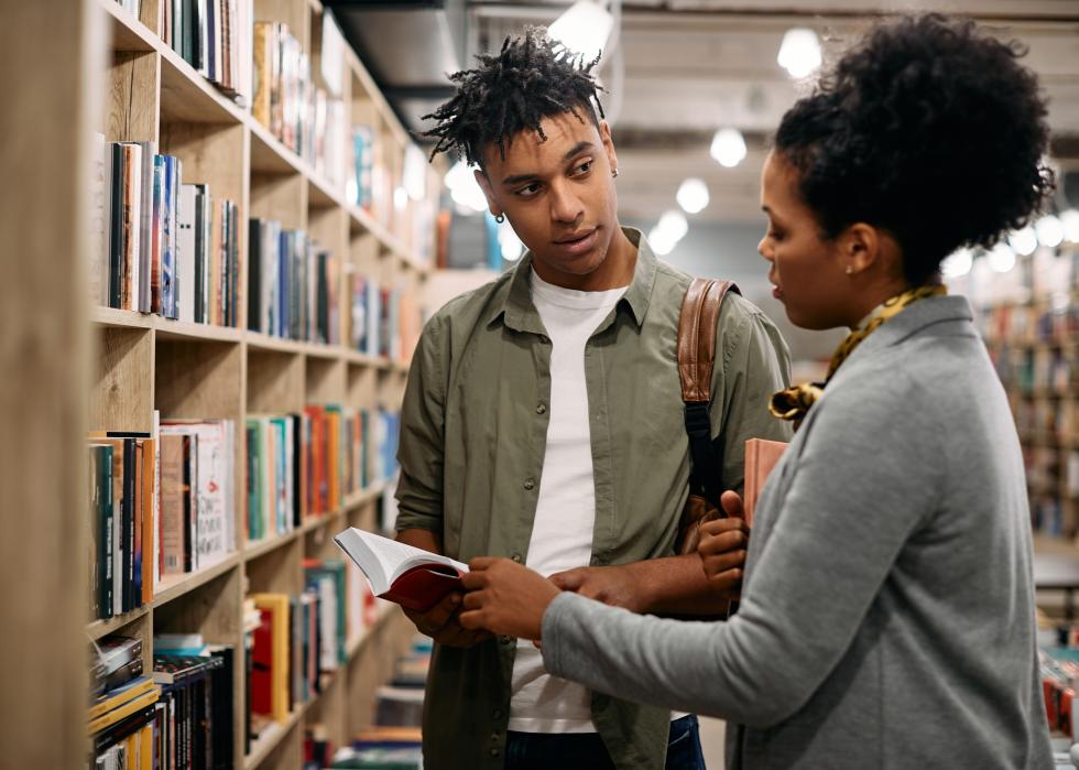 College-aged student talking to a woman in a librarian.