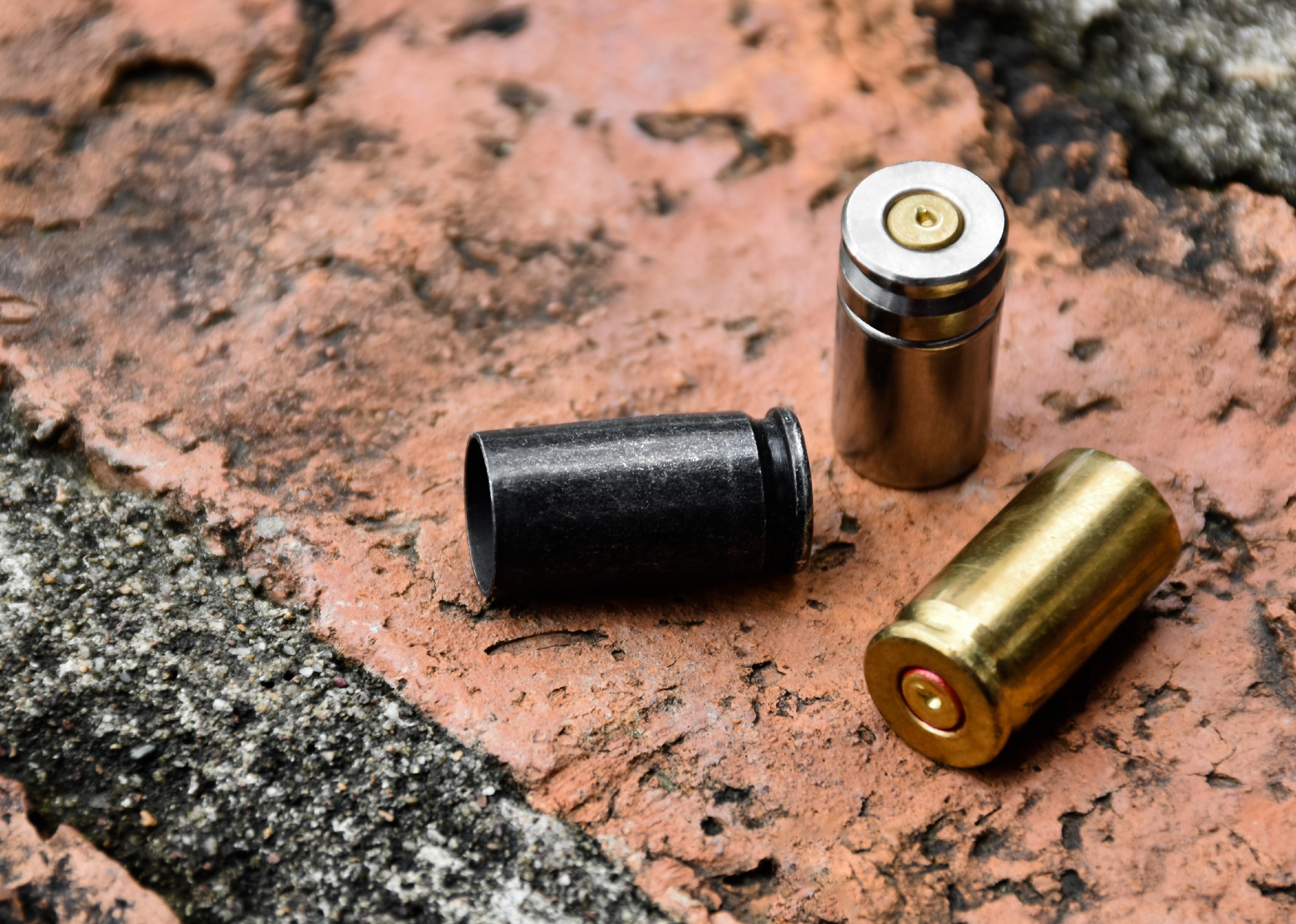 9mm pistol bullets and bullet shells on brick floor.