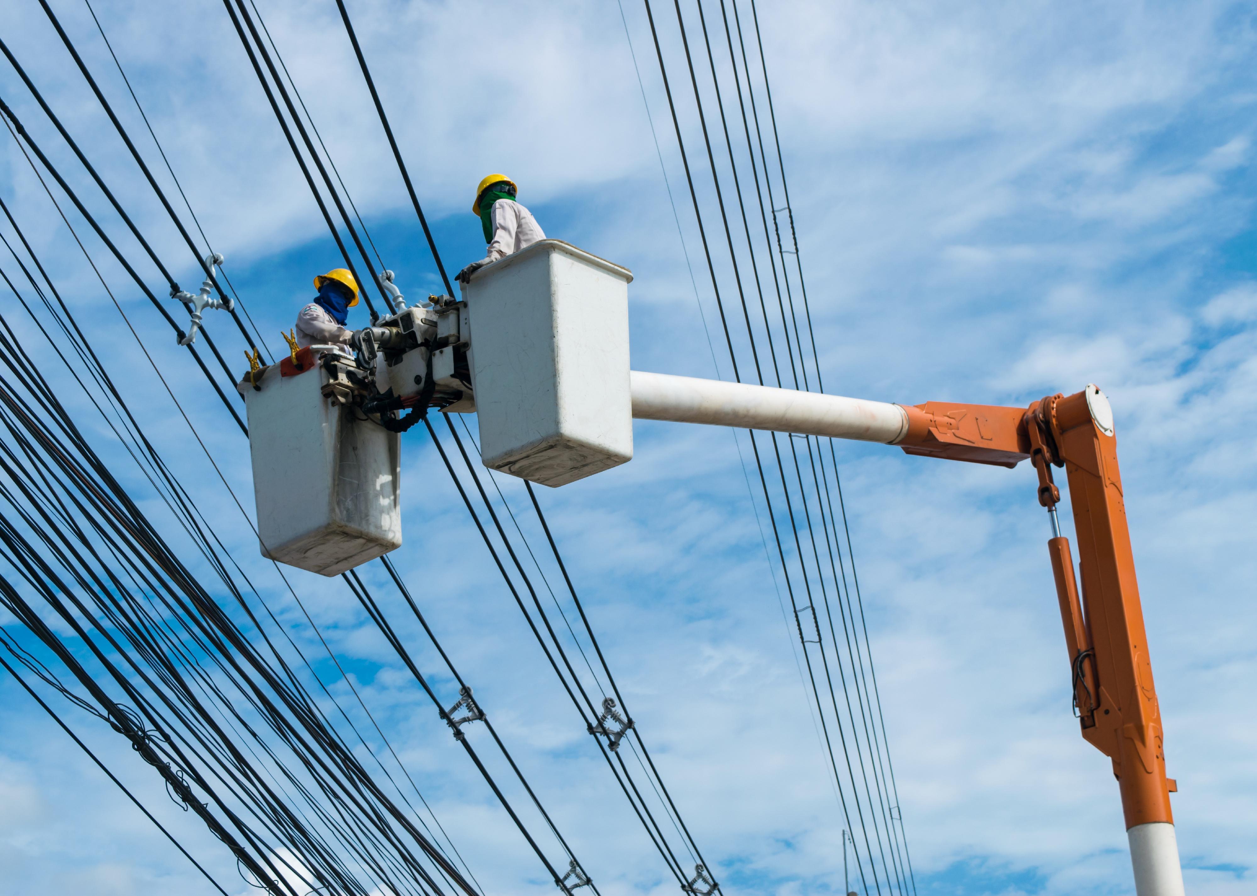 Electricians wiring cable to install and repair power lines.