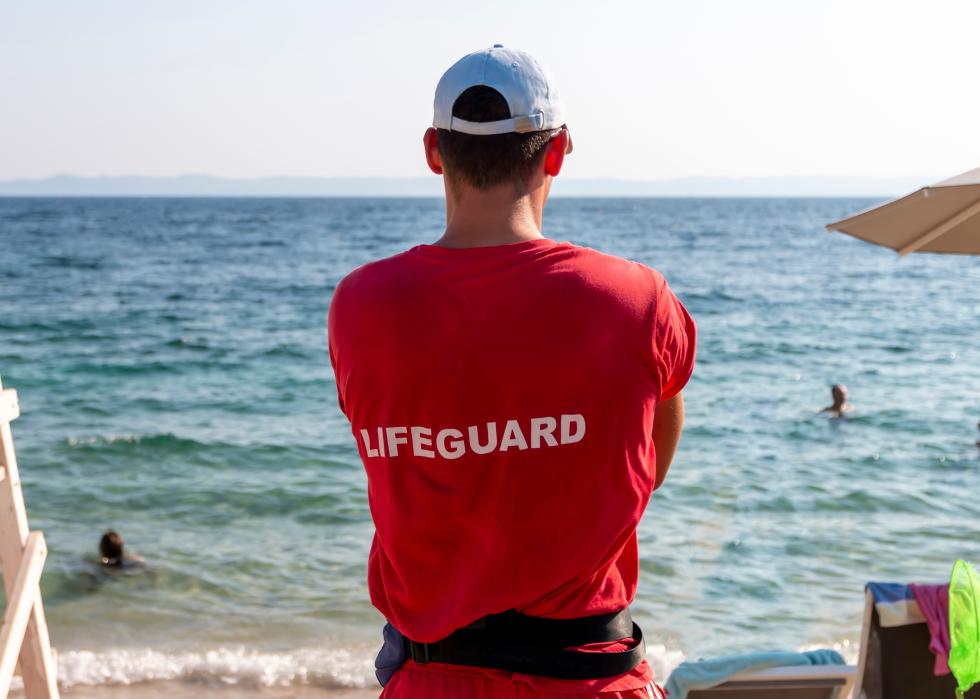 A lifeguard looking out toward the sea where a person is swimming.