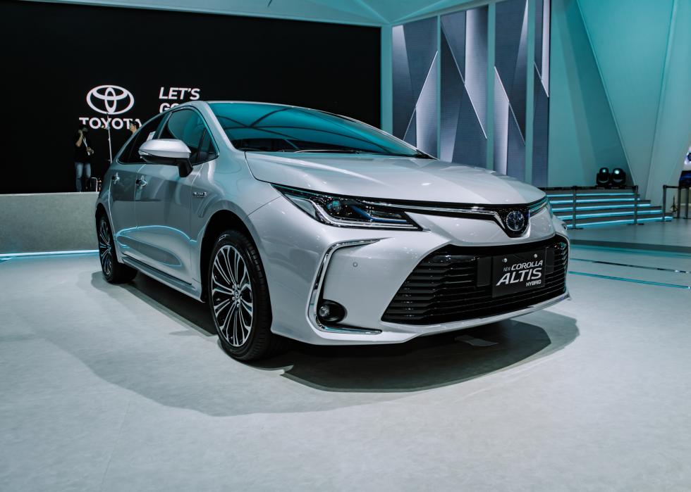 A light silver Corolla Altis on display in a showroom at an event.