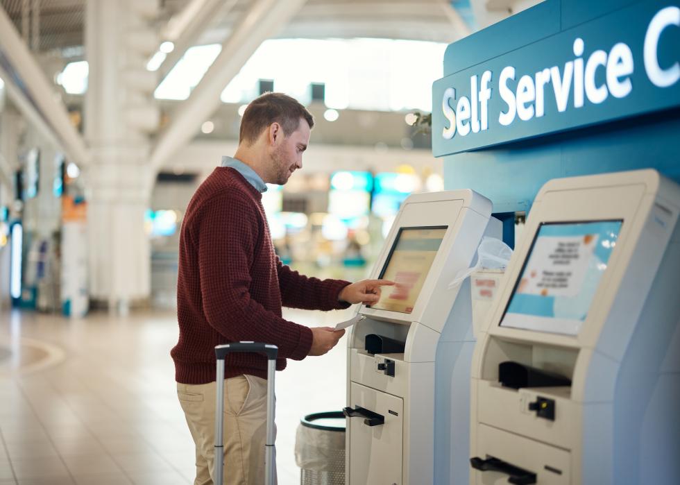 Man in the airport at a self service kiosk for check in.