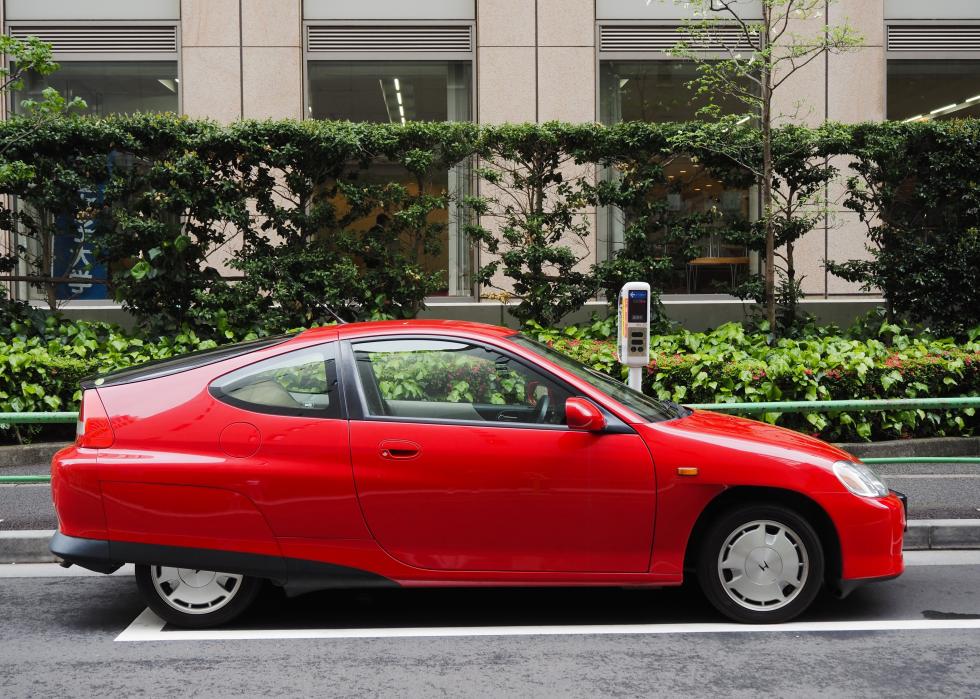 A red Honda Insight hybrid car parked in central Tokyo.