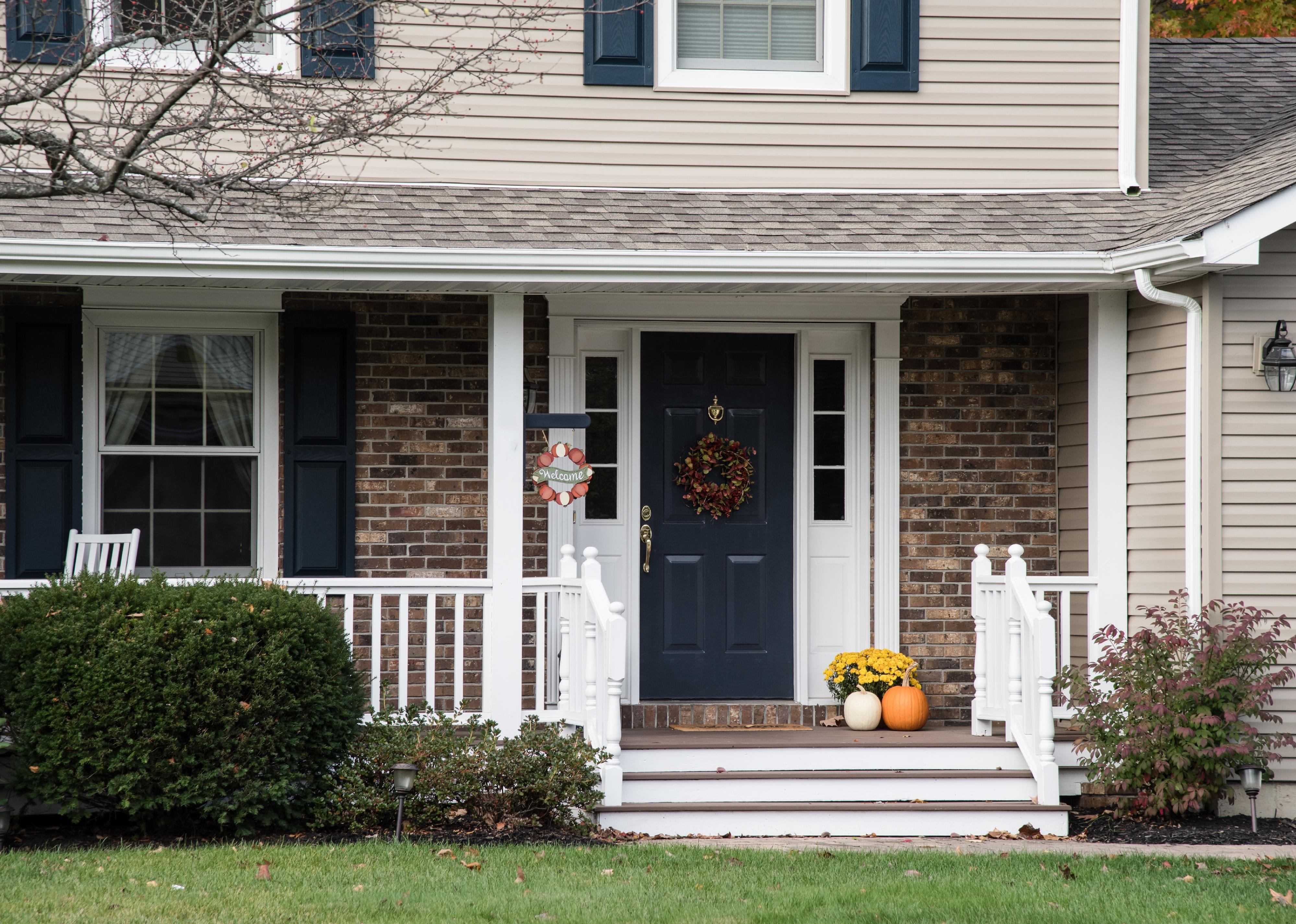 Front porch of suburban home decorated for fall holidays.