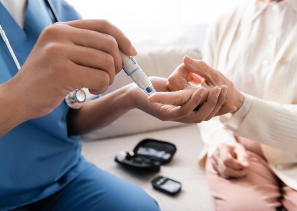 Nurse taking blood sample of an older woman.