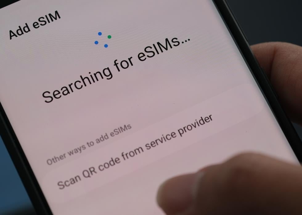 Hands holding an android smartphone with a message that says, add eSIM, searching for eSIMS.