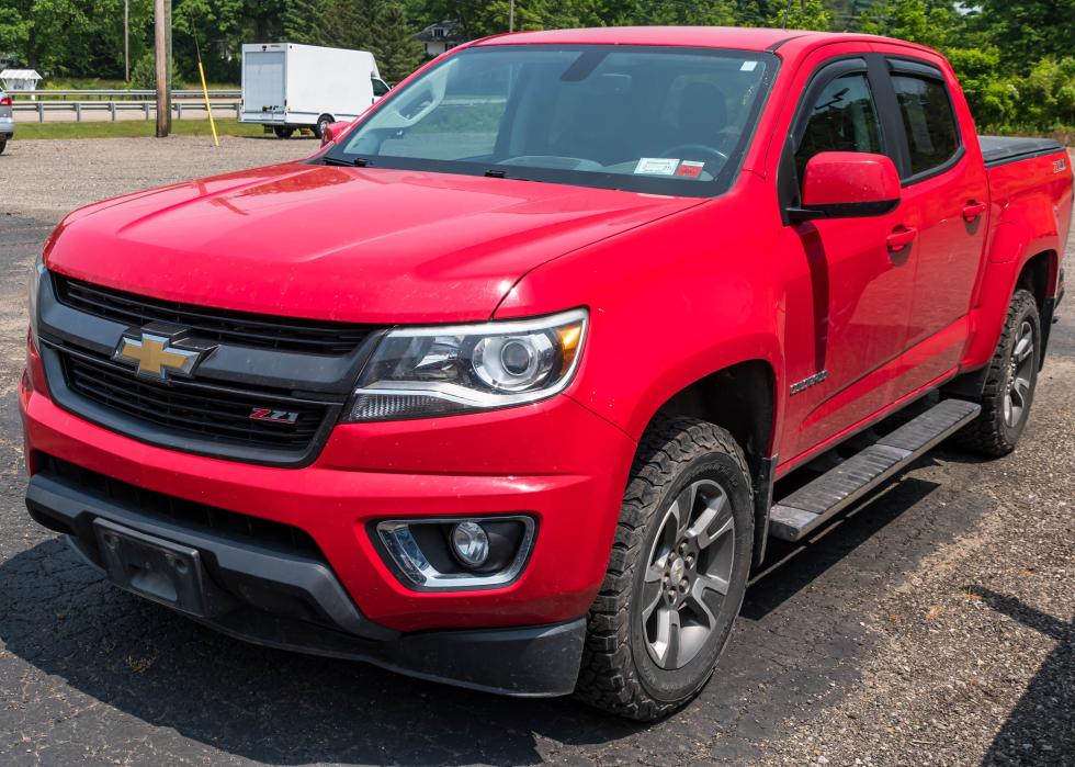 A red Chevrolet Colorado four door pick up for sale at a dealership.