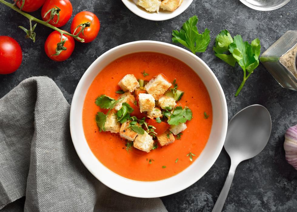 Gazpacho soup in bowl over dark stone background.