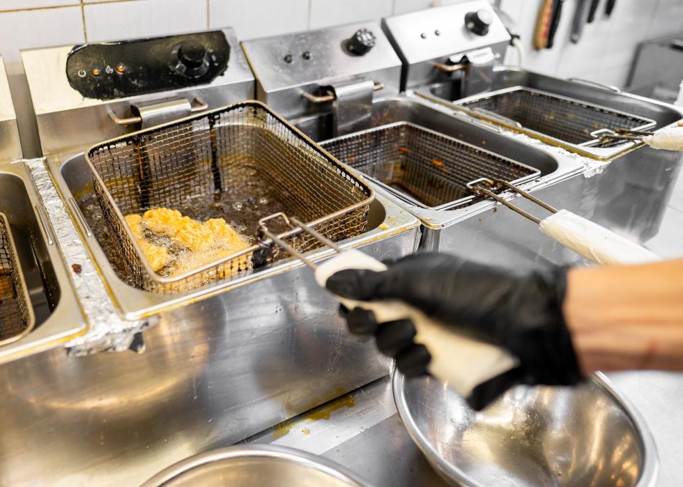 A commercial kitchen deep fryer cooking chicken pieces.