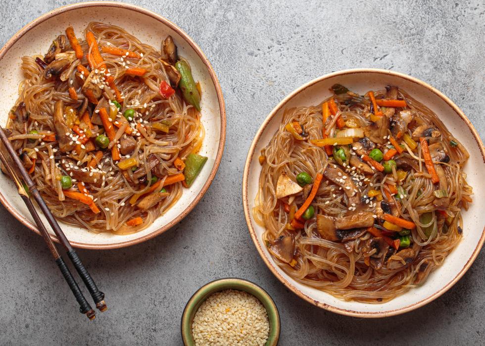 Two bowls of japchae, korean glass noodles stir fry.